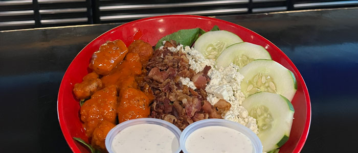From the Daisy's Garage salad menu is the Boneless buffalo wings, tomato, onion, bacon, bleu cheese crumbles and cucumbers